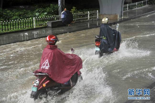 6月24日，在南宁市竹溪立交桥附近，市民通过积水严重路段。