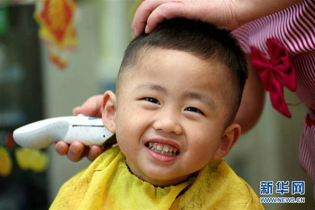 3月8日，在山东枣庄市一家婴幼儿理发店，理发师为一名小朋友“剃龙头”。