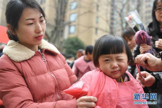 3月8日，在合肥市滨湖欣园社区，志愿者为朱杨妮小朋友“剃龙头”。