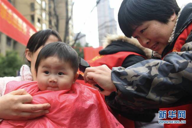 3月8日，在合肥市滨湖欣园社区，志愿者为刘玉恒小朋友“剃龙头”。