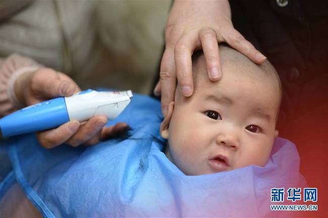 3月8日，在湖北襄阳市保康县一家婴幼儿理发店里，理发师为一名小朋友在“剃龙头”。