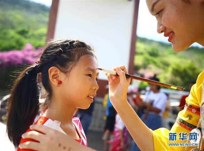 6月7日，在海南省三亚市南山文化旅游区，工作人员为小朋友点雄黄。新华社发（陈文武摄）