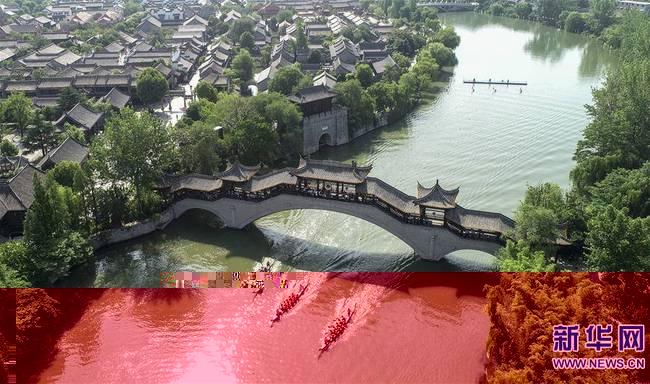 6月7日，人们在山东省枣庄市台儿庄古城古运河道上划龙舟（无人机拍摄）。新华社发（高启民摄）