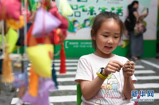 6月7日，小朋友在浙江省杭州市青少年发展中心“Do都城”举办的体验活动中编制五色绳。