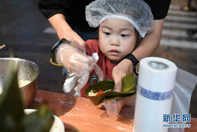 6月7日，小朋友在浙江省杭州市青少年发展中心“Do都城”举办的体验活动中包粽子。