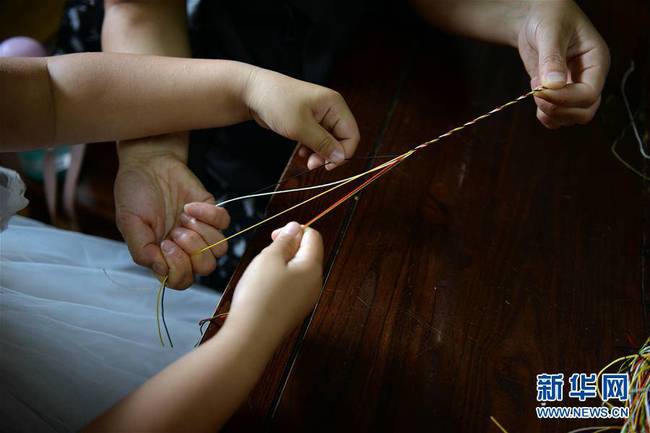 6月7日，小朋友和家长在山东聊城海源阁编制五彩绳。新华社发（孔晓政摄）